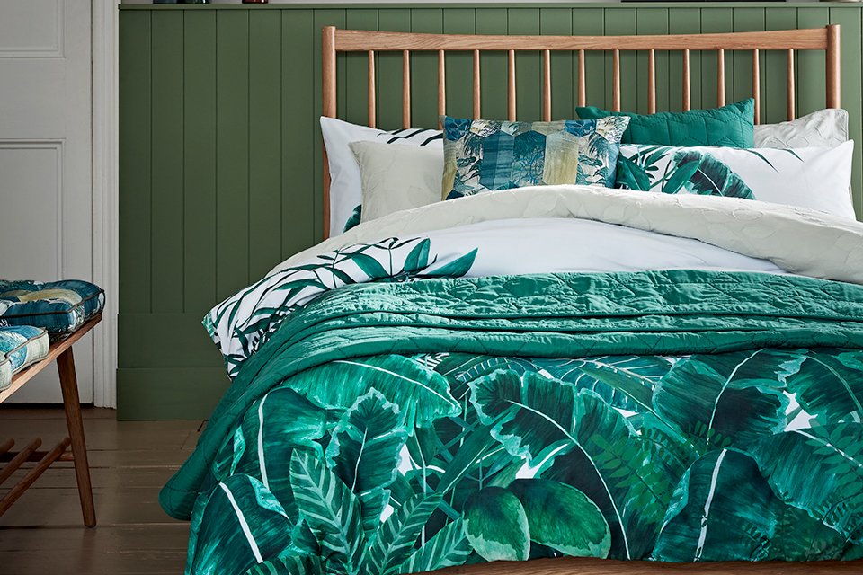 Wooden bed with green leafy bedding.